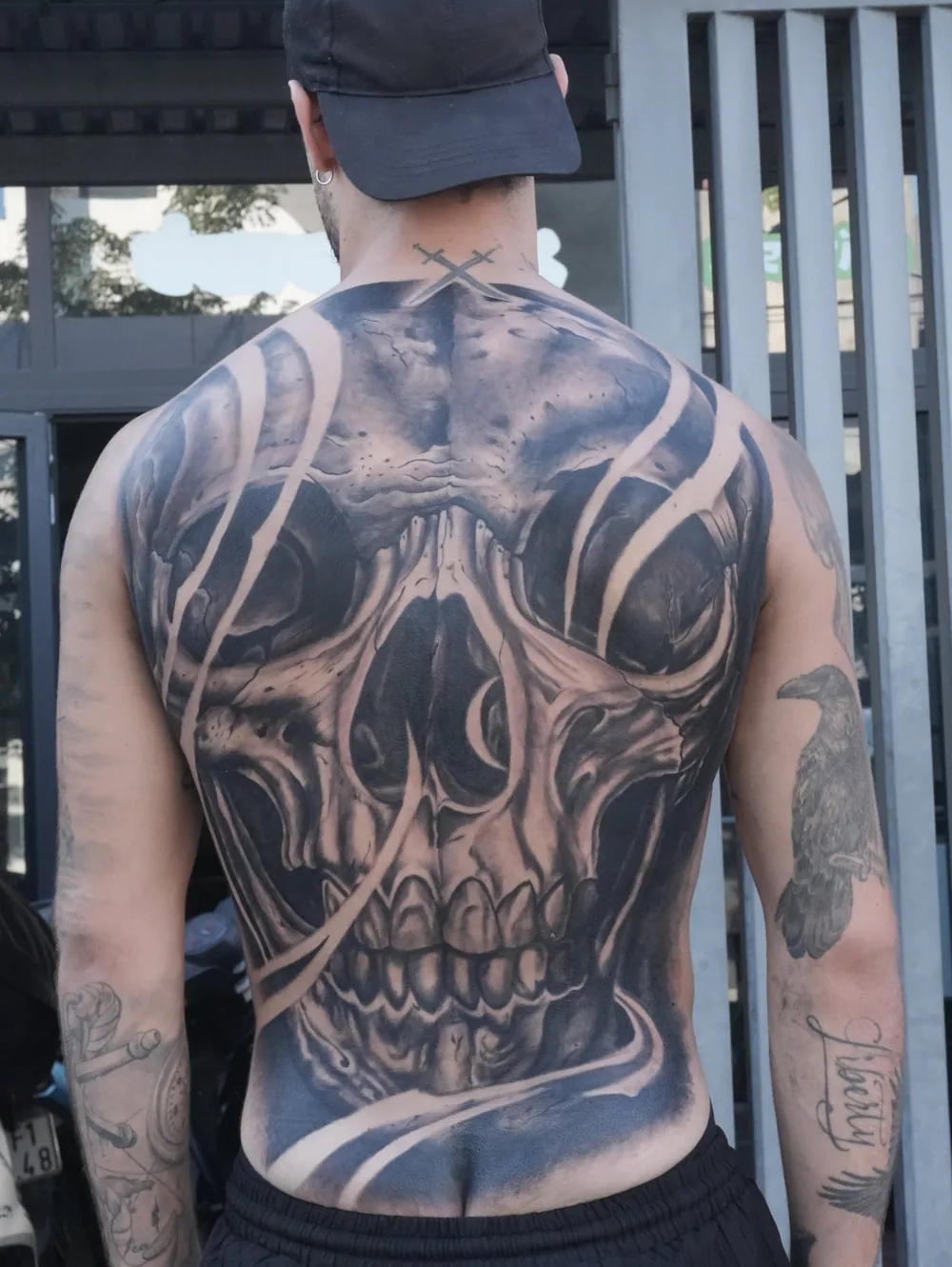 Full-back skull tattoo in black and grey, seen from behind